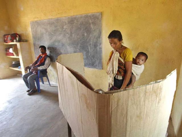 A tribal woman carries her baby while casting her vote during Lok Sabha elections at a polling station at Putsari village in Assam. (Reuters photo)