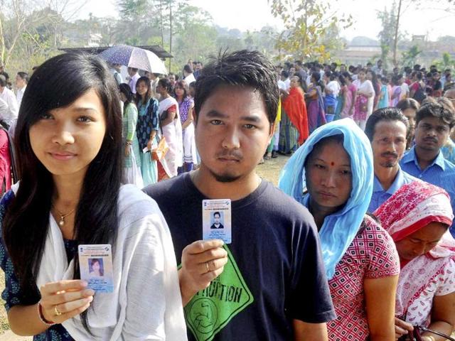 People show their voter identity cards as they wait in queues to cast their votes for Lok Sabha polls at a polling station, at Diphu in Karbi Anglong district of Assam. (PTI photo)