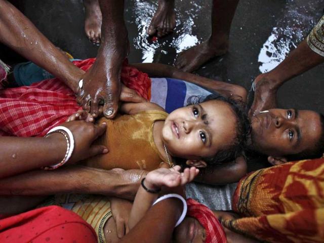 A Hindu holy man (not pictured) touches a girl with his foot as part of a ritual to bless her during a religious procession to mark the Gajan festival in Kolkata. (Reuters photo)