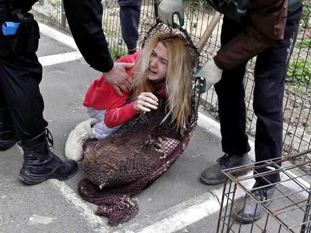A woman embraces her dog that was taken from the streets by dog catchers who she tries to convince to release in Bucharest. (Reuters)