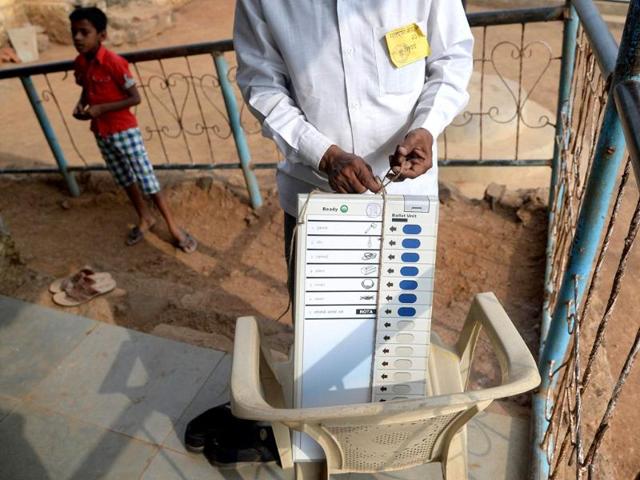 An election official prepars a model of an electronic voting machine to be hung outside a polling station in the Shirgaon village of Pune district. (AFP photo)