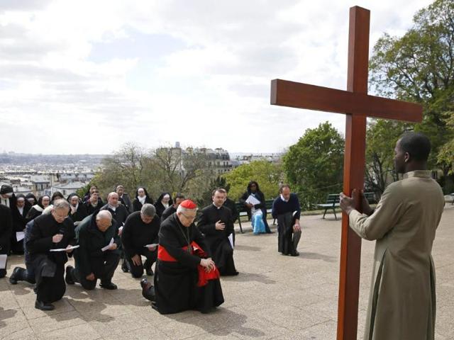 France's Cardinal Andre Vingt-Trois kneels in front of a wooden cross as he attends a Good Friday procession in front of the Sacre-Coeur basilica on the Montmartre hill of Paris. (AFP photo)