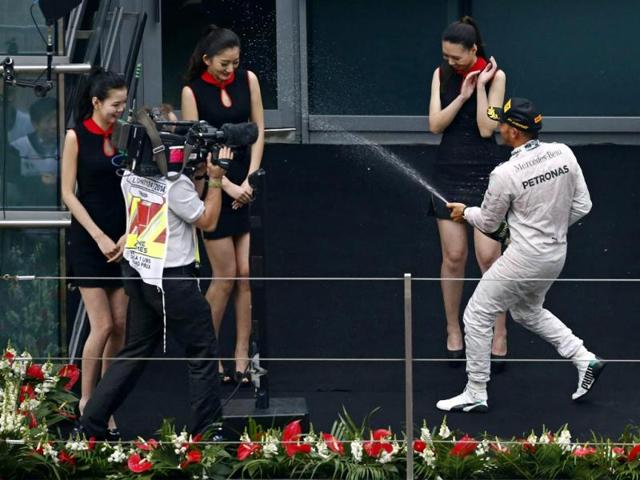 First-placed Mercedes Formula One driver Lewis Hamilton of Britain sprays champagne to grid girls as he celebrates his win after the Chinese F1 Grand Prix at the Shanghai International circuit. (Reuters Photo)