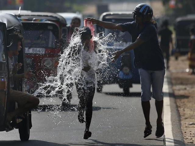 A man pours water on a competitor during a road race as part of traditional festival games to celebrate the Sinhala, the Hindu and Tamil New Year, in Homagama. (Reuters Photo)