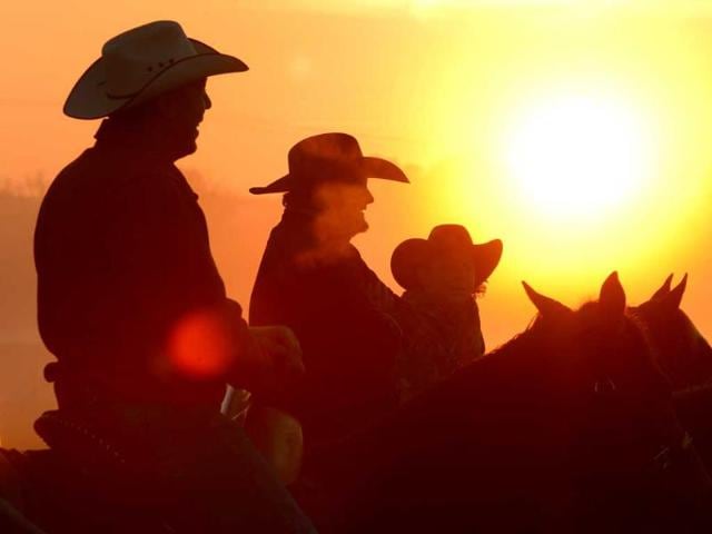 Worshippers join together for a sunrise service at the No Fences Cowboy Church Easter Sunday in Falkville, Alabama. Cowboys on horseback greet the sunrise and arriving worshippers. (AP Photo)