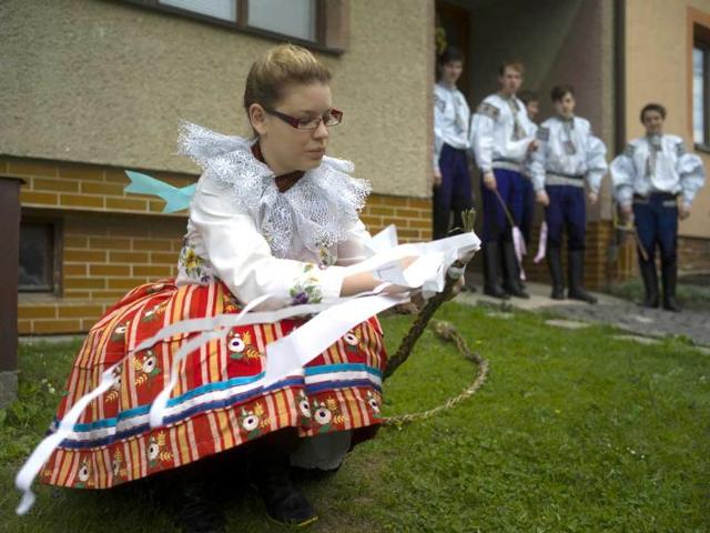 A girl ties a ribbon on a whip after she was symbolically beaten by boys in traditional dresses in order to get colored eggs in the village of Vlcnov (AFP Photo)
