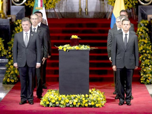 Colombia's President Juan Manuel Santos, left, and Mexico's President Enrique Pena Nieto, right, stand next to the urn containing the ashes of Gabriel Garcia Marquez in the Palace of Fine Arts.(AP Photo)