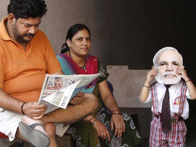 A school going child wears a mask of BJP PM candidate Narendra Modi at bus stop in Varanasi. (HT photo/Arvind Yadav)