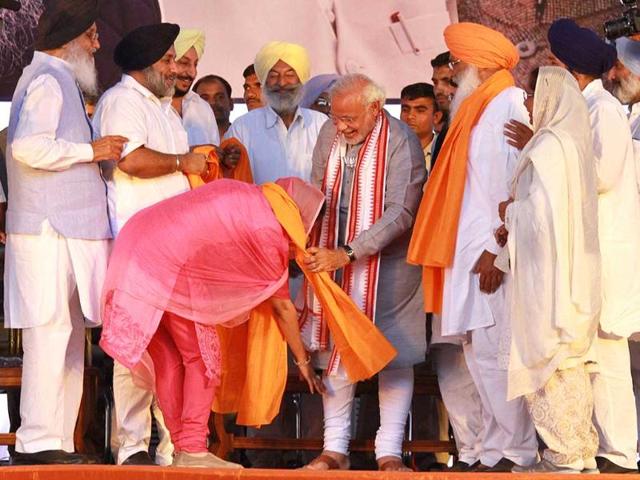 SAD candidate Harsimrat Kaur Badal touches the feet of BJP’s PM candidate Narendra Modi during a rally in her support in Bathinda. (HT photo/Kulbir Beera)