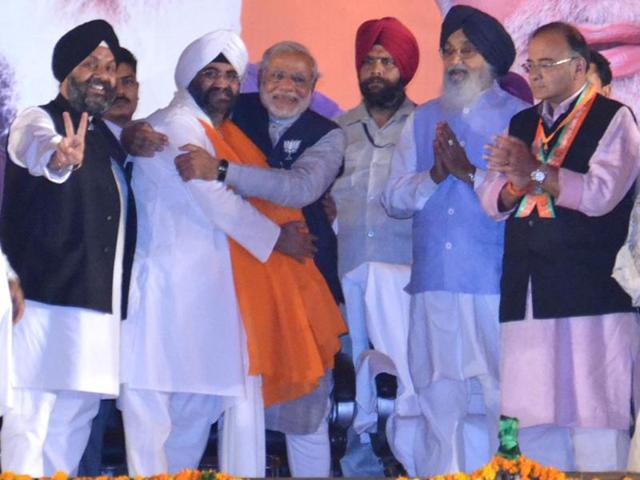 BJP's PM candidate Narendra Modi hugs Daljit Singh, PM Manmohan Singh's step-brother who joined BJP, during a election campaign rally in Amritsar. (HT Photo/Sameer Sehgal)
