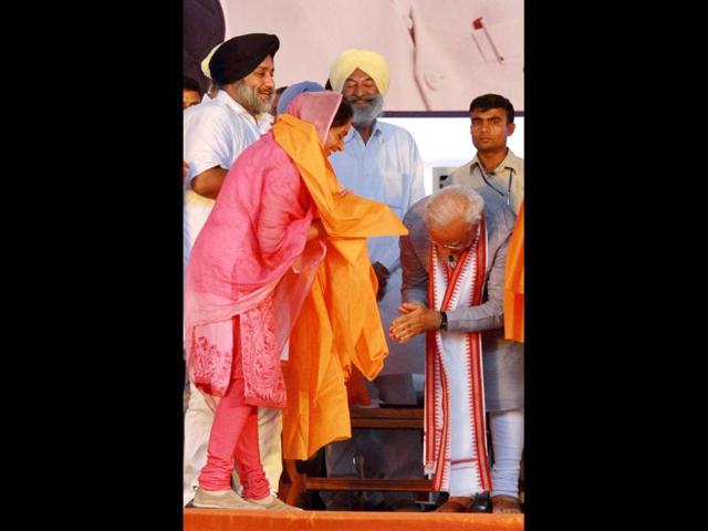 BJP’s PM candidate Narendra Modi gestures after SAD candidate Harsimrat Kaur Badal touched his feet during an election rally in Bathinda. (PTI Photo)