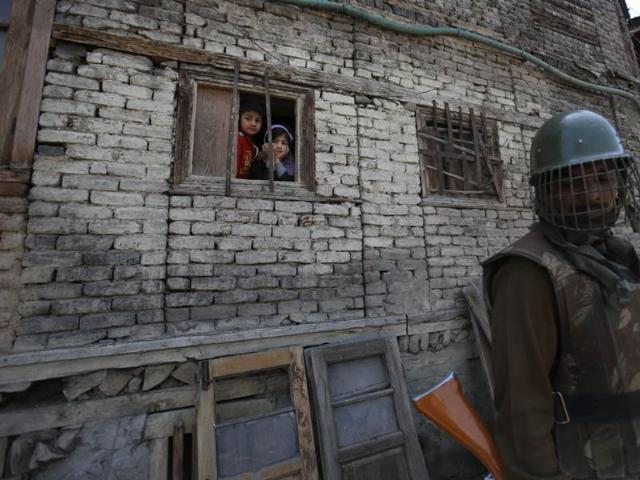 An Indian paramilitary soldier stands guard as Kashmiri children look through a window of their house during an election campaign rally by Jammu-Kashmir state's governing National Conference party leader Farooq Abdullah, in Srinagar. (AP Photo)