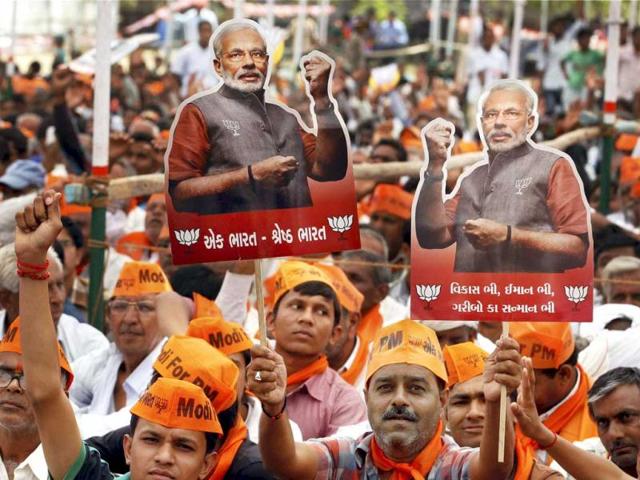 BJP supporters hold cut-outs of Narendra Modi during an election rally at Kharelu in Mahesana. (PTI Photo)