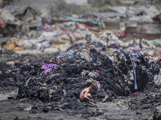 An Indian boy looks for metal scrap amid charred debris after a fire at a slum in Ghaziabad, outskirts of New Delhi, India. (AP Photo)