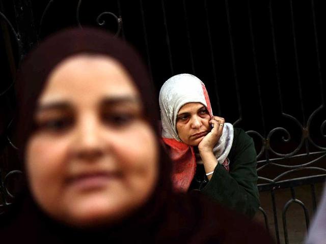An Egyptian woman looks at women overcome by emotion after a judge in Egypt sentenced to death 683 alleged supporters of the country's ousted Islamist president over acts of violence and the murder of policemen in the latest mass trial in the southern city of Minya, Egypt. (AP Photo)