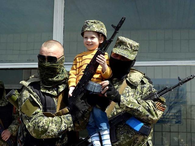 Pro-Russian armed men in military fatigues pose for a photograph with a child as they stand guard outside a regional administration building seized in the night by pro-Russian separatists, in the eastern Ukrainian city of Konstantinovka. (AFP Photo)