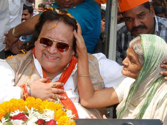 Singer and BJP candidate Bappi Lahiri seeks blessings from an elderly woman during his election campaign at Bally in Sreerampore constituency. (PTI photo)