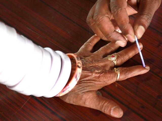 A polling officer marks the finger of a tribal woman with indelible ink inside a polling station on the outskirts of Hyderabad. (Results Photo)