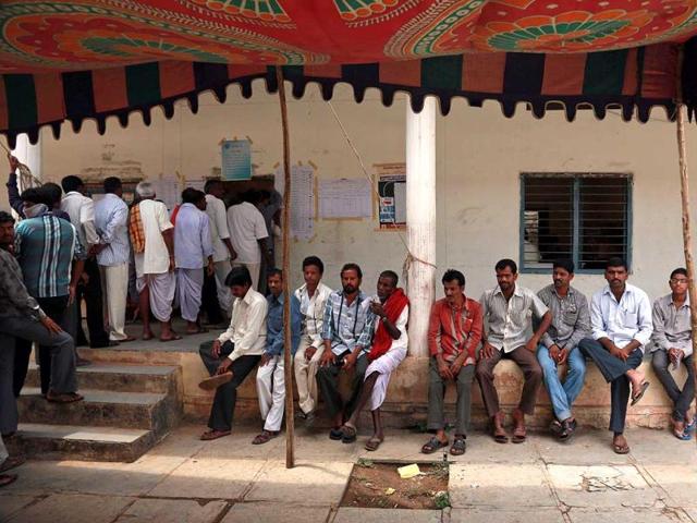 Men stand in a queue to cast their votes, as others rest at a polling station on the outskirts of Hyderabad. (AP Photo)