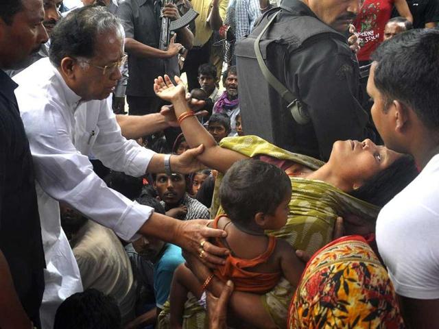 Assam Chief MinisterTarun Gogoi reacts as a victim of separatist violence collapses as other residents gather at Narayanguri in the district of Baska. (AFP Photo)