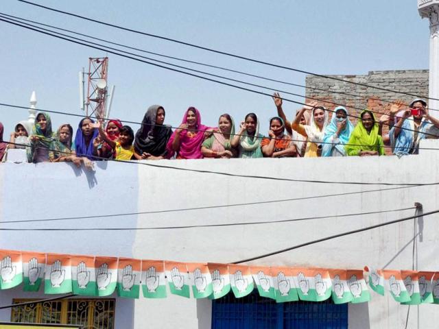 Women stand on a house-roof to take a glimpse of Congress vice-president Rahul Gandhi during his road show in Varanasi. (PTI photo)