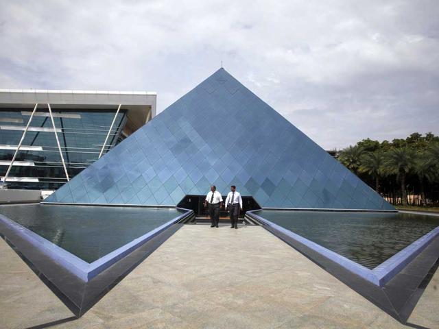 Employees walk in front of a pyramid-shaped building at the Infosys campus in the Electronic City area of Bangalore.(Reuters File Photo)