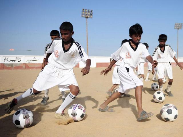 Pakistani local youth participate in a training session on a dusty pitch in a Karachi slum in the famous white shirt of Real Madrid. (AFP Photo)