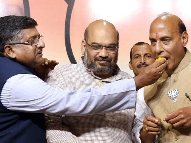 BJP leader Ravi Shankar Prasad offers sweets to party president Rajnath Singh as BJP's UP election incharge Amit Shah looks on during a press conference after the party's huge victory in the Lok Sabha elections. (PTI Photo)