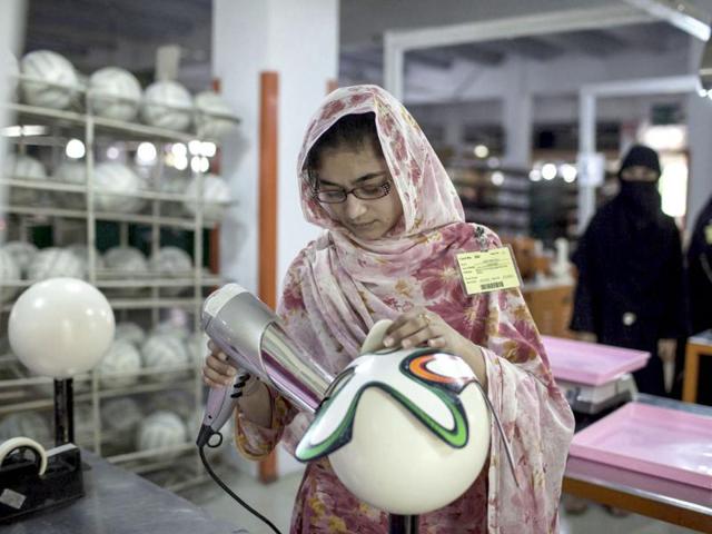 An employee uses hot air as she sticks outer panels on a soccer ball inside the soccer ball factory that produces official match balls for the 2014 World Cup in Brazil, in Sialkot. (Reuters photo)