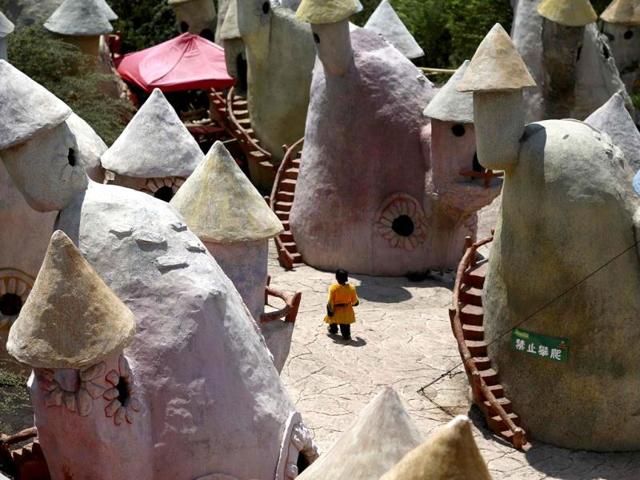 A dwarf walks in between mushroom-shaped houses after performances at Kunming World Butterflies Garden, Yunnan province. (Reuters)