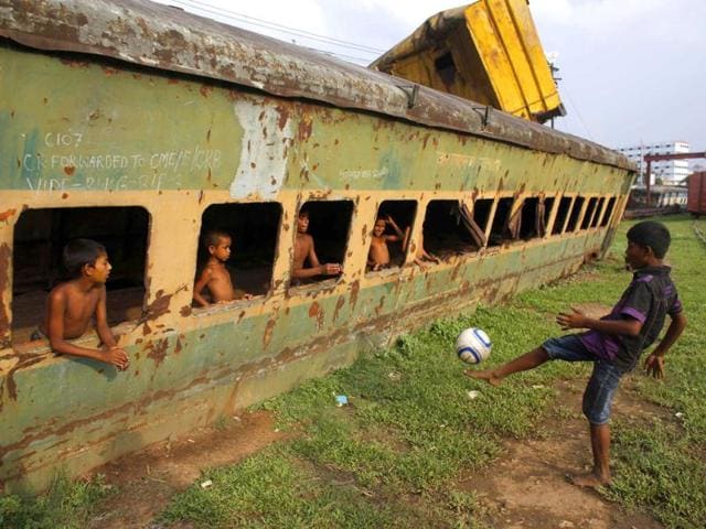 Children play football in front of an abandoned train compartment next to a railway track in Dhaka. (Reuters Photo)