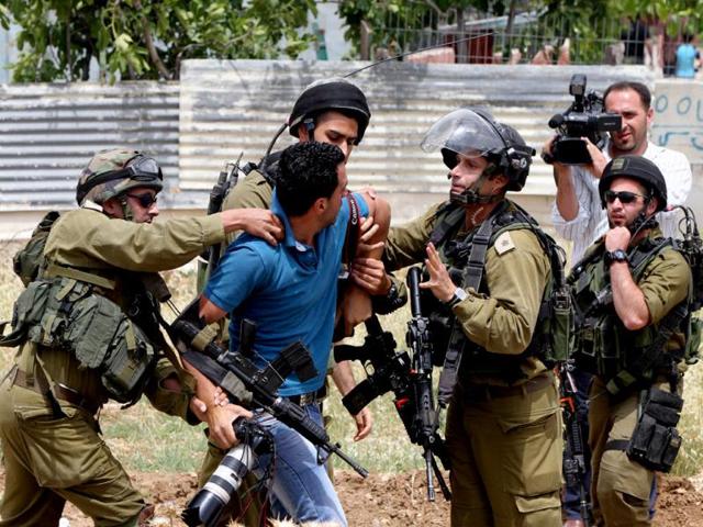 Israeli soldiers detain a photographer during a protest in support of Palestinian prisoners on hunger strike in Israeli jails at the al-Aroub Palestinian refugee camp. (AFP Photo) Israeli soldiers detain a photographer during a protest in support of Palestinian prisoners on hunger strike in Israeli jails at the al-Aroub Palestinian refugee camp. (AFP Photo)