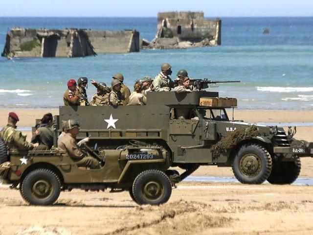 Vintage US army vehicles are driven by history enthusiasts past the remains of Mulberry harbour on the former D-Day landing zone of Gold Beach in Asnelles June 6, 2014. World leaders and veterans gathered by the beaches of Normandy on Friday to mark the 70th anniversary of World War Two's D-Day landings. (Reuters)