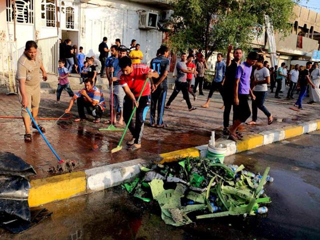 People clean up in the aftermath of a suicide bomb attack in Baghdad's Sadr City, Iraq. A suicide bomber set off his explosive belt inside a tent where tribesmen were meeting to solve a tribal dispute, killing and wounding scores of people, authorities said. (AP/PTI Photo)