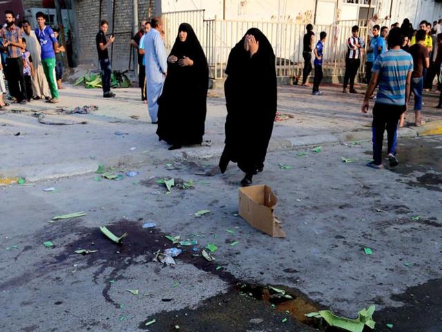 Civilians inspect the aftermath of a suicide bomb attack in Baghdad's Sadr City, Iraq, Wednesday, June. 11, 2014. A suicide bomber set off his explosive belt inside a tent where tribesmen were meeting to solve a tribal dispute, killing and wounding scores of people, authorities said. (AP Photo)