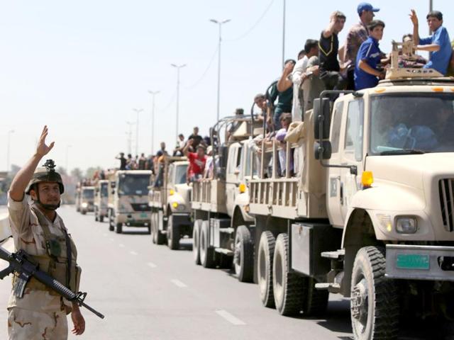 An Iraqi soldier waves as trucks carrying volunteers to fight alongside the Iraqi security forces against Jihadist militants leave a recruitment center on June 15, 2014 in the Iraqi capital Baghdad. Faced with a militant offensive sweeping south toward Baghdad, Prime Minister Nuri al-Maliki announced the Iraqi government would arm and equip civilians who volunteer to fight, and thousands have signed up. AFP Photo