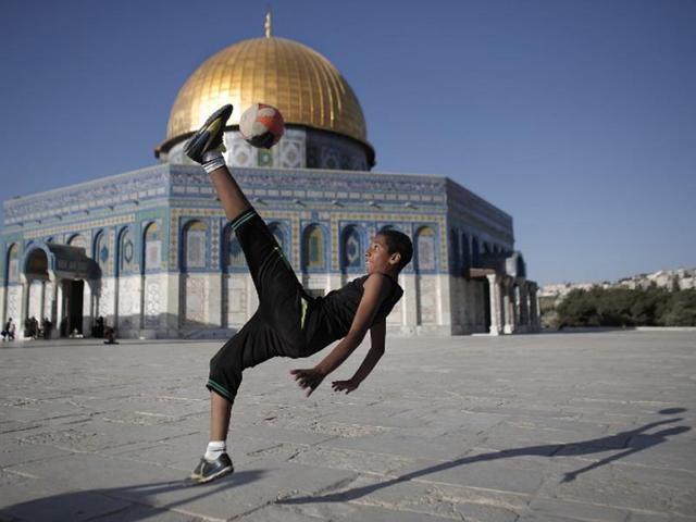 Jerusalem: A Palestinian youth plays football in front of the Dome of the Rock on the Al-Aqsa mosque compound in the Old city of Jerusalem. (AFP PHOTO)