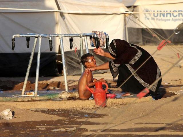 An Iraqi woman bathes her son at a camp for displaced Iraqis who fled from Mosul and other towns following attacks by Sunni insurgents. (AP photo)