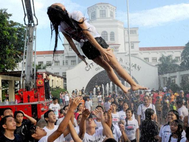 A woman hoisted into the air by friends after they were sprayed with water as residents celebrate the feast day of St John the Baptist in Manila. (AFP photo)