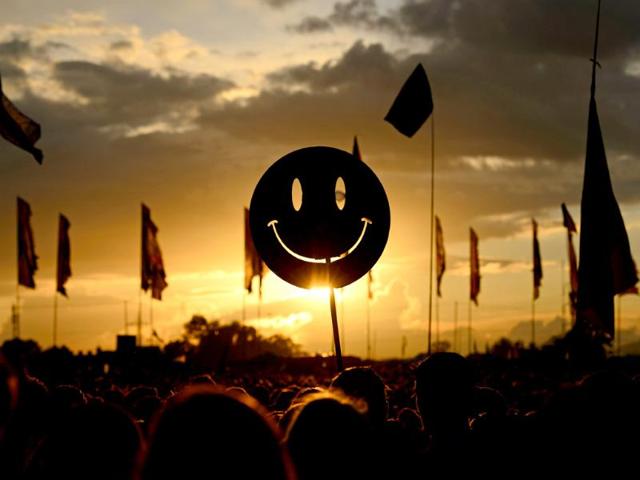 A smiley face sign is carried through the crowds as the sun sets on the first official day of the Glastonbury Festival of Music and Performing Arts in Somerset, southwest England. (AFP photo) A smiley face sign is carried through the crowds as the sun sets on the first official day of the Glastonbury Festival of Music and Performing Arts in Somerset, southwest England. (AFP photo)