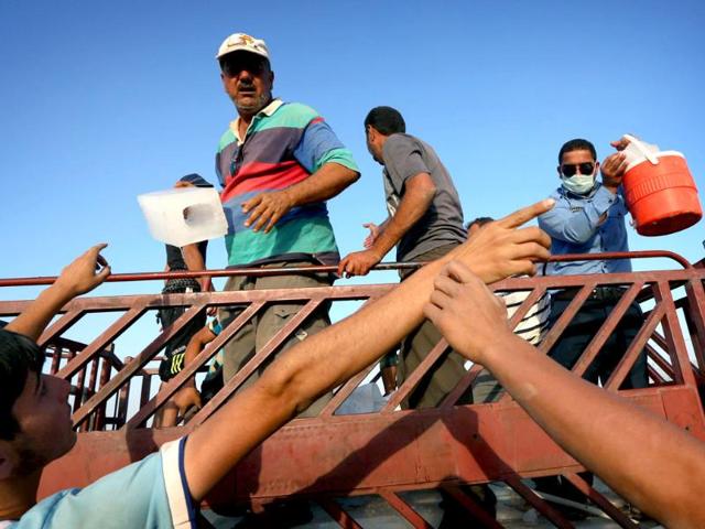 Iraqi families fleeing violence in the northern city of Tal Afar, are given iced water as they arrive at the Kurdish checkpoint in Aski kalak, 40 km West of Arbil, in the autonomous Kurdistan region. (AFP photo)