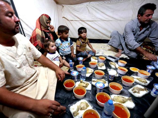 Displaced Iraqis ready to break their fast during the holy Muslim month of Ramadan, as they sit in a tent provided by the UN refugee agency at a temporary camp set up to shelter people fleeing violence in northern Iraq in Aski kalak, 40 kms west of the Kurdish autonomous region's capital Arbil. (AFP photo)