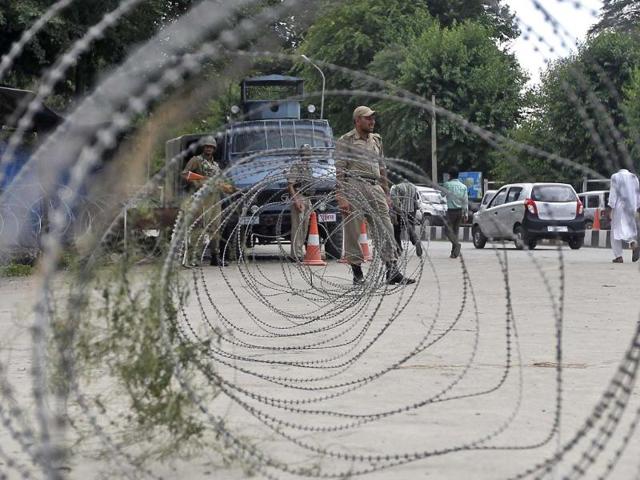 A cop stands guard next to concertina wires during a strike in Srinagar. PM Modi was greeted by near-empty streets lined by security personnel on his first official visit to Kashmir, as separatists enforced a strike. (Reuters photo)