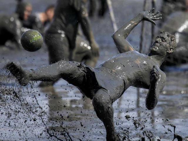 A participant kicks the ball during a handball match at the "Wattoluempiade," or Mud Olympics, in the northern German city of Brunsbuettel. (Reuters photo)