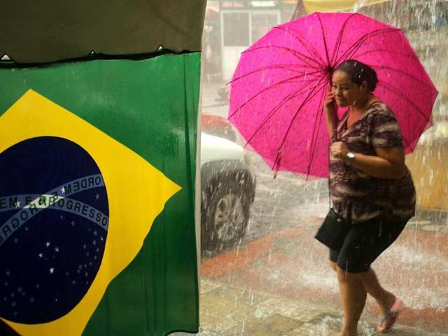 A woman reacts as she walks in the rain near a Brazilian flag in Manaus. (Reuters)