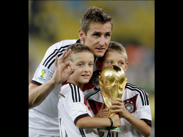 Germany's Miroslav Klose and his sons pose with the World Cup trophy following their 1-0 victory over Argentina after the World Cup final soccer match between Germany and Argentina at the Maracana Stadium in Rio de Janeiro, Brazil on July 13, 2014. (AP Photo/Natacha Pisarenko)