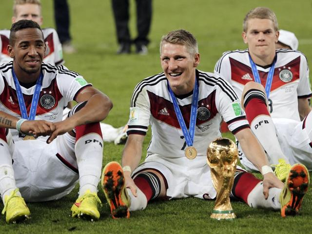 Germany's Jerome Boateng, left, and Bastian Schweinsteiger, center, sit on the pitch with the trophy after the World Cup final between Germany and Argentina on July 13, 2014. Germany won the match 1-0. (AP Photo/Matthias Schrader)