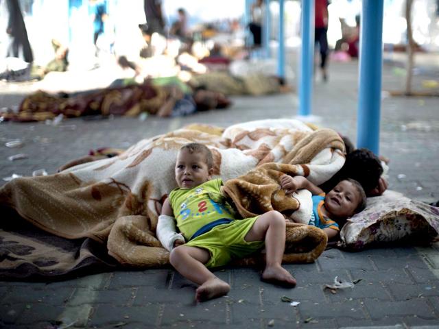 Palestinian children rest at a UN school after evacuating their homes near the border. (AFP Photo)