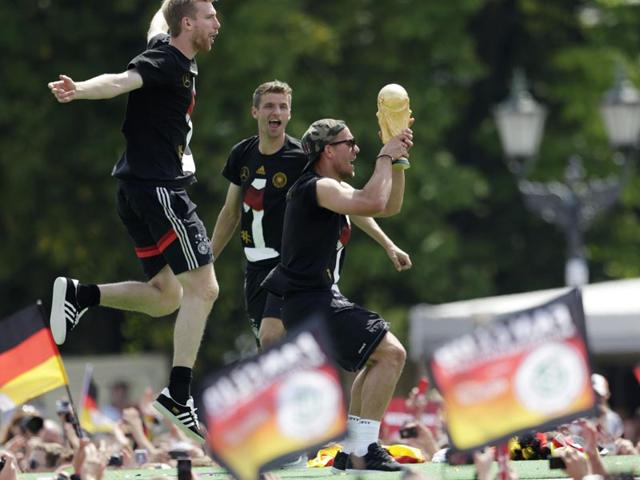 Lukas Podolski holds the trophy during a fan party after the arrival of the German national soccer team in Berlin on July 15, 2014. (AP Photo/Petr David Josek) 