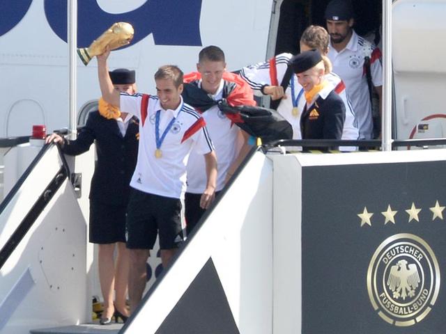 German national football players from left: Philipp Lahm Bastian Schweinsteiger,Thomas Mueller and Sami Khedira, arrive with the trophy at Tegel airport in Berlin on July 15, 2014. The World Cup-winning team has returned home from Brazil to celebrate the country’s fourth title with huge crowds of fans. (AP Photo/Bernd von Jutrczenka) 
